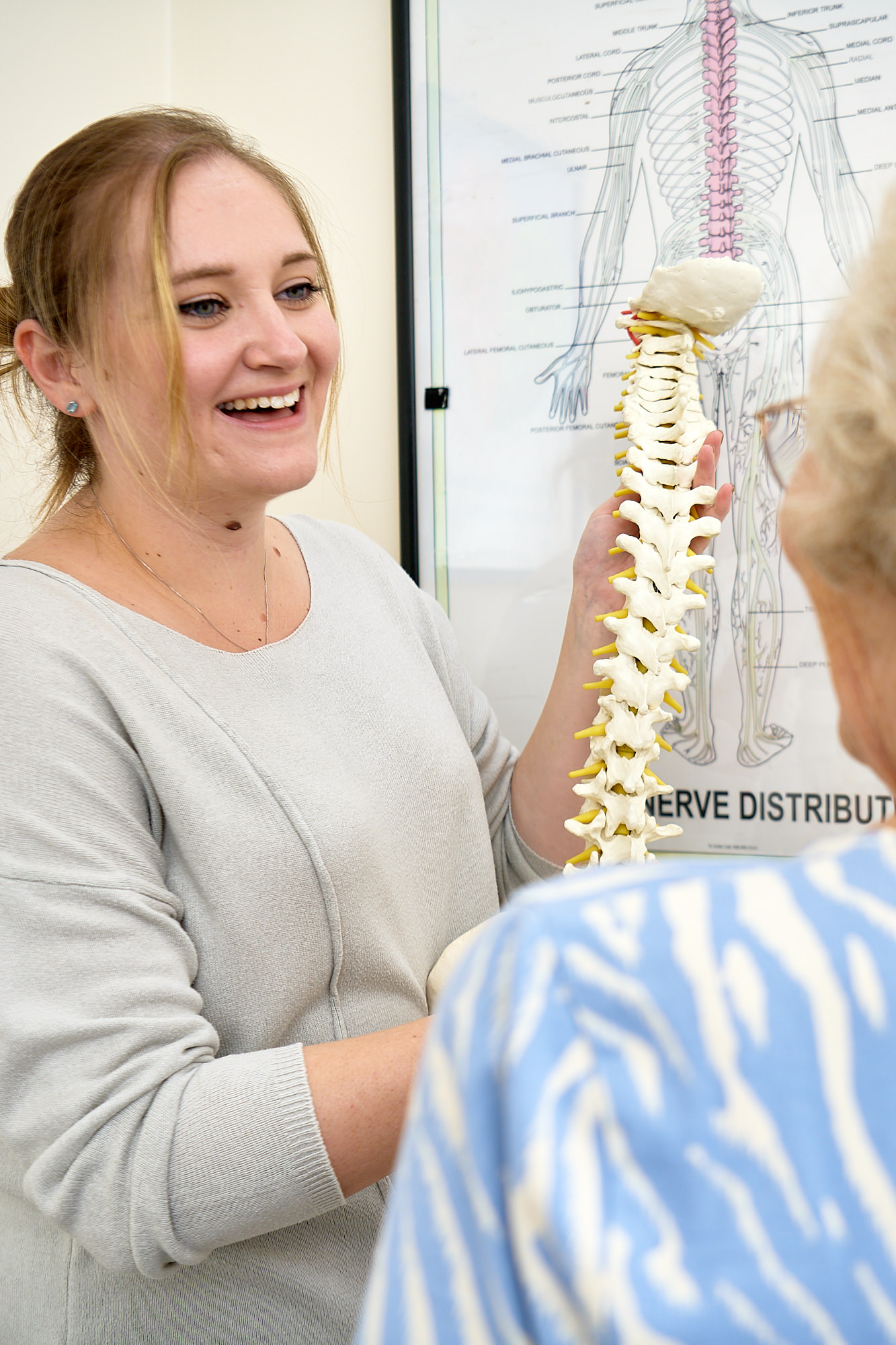 Image of a chiropractor showing a spinal model to a patient